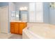 Bathroom with corner bathtub, wood cabinets, and tiled floors at 15890 Sw 11Th Terrace Rd, Ocala, FL 34473