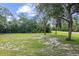 Backyard with grassy area, mature trees, and road at 49 Fisher Way, Ocklawaha, FL 32179