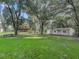 Spacious backyard with a shed, lush greenery, and large oak trees at 11831 Sw Highway 484, Dunnellon, FL 34432