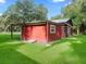 Red barn with white trim, a large door, and a window, nestled in a grassy field at 11831 Sw Highway 484, Dunnellon, FL 34432