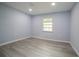 Light blue bedroom with grey wood-look flooring and a window at 1750 Ne 180Th St, Citra, FL 32113