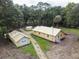 Aerial view of a yellow house with detached garage and shed on a wooded lot at 1750 Ne 180Th St, Citra, FL 32113