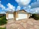 Tan house with double white garage doors and a landscaped yard at 16376 Sw 13Th Ter, Ocala, FL 34473