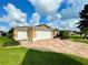 Tan house with double garage doors and a patterned driveway at 16376 Sw 13Th Ter, Ocala, FL 34473
