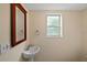 Small bathroom with pedestal sink, wood-framed mirror, and a window at 10 Se Chinica Drive, Summerfield, FL 34491