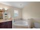 Bathroom with corner bathtub, vanity, and toilet at 10 Se Chinica Drive, Summerfield, FL 34491