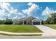 One-story house with a taupe exterior, two-car garage, and green lawn at 25 Nw 45Th Loop, Ocala, FL 34475