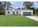 One-story home with gray garage door, white exterior, and lush green lawn at 7171 Sw 133Rd Ln, Ocala, FL 34473