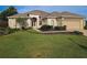 Tan colored house with a large yard and two-car garage at 9240 Se 128Th Ln, Summerfield, FL 34491