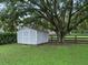 Gray storage shed nestled under a large oak tree in the backyard at 1620 Nw 73Rd Ter, Ocala, FL 34482