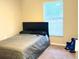 Well-lit bedroom with gray comforter, black headboard, and window blinds at 13709 Se 40Th Ct, Summerfield, FL 34491