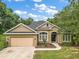 House exterior with a tan exterior, a two-car garage, and landscaping at 9680 Ne 25Th Ct, Anthony, FL 32617