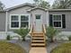 Front entrance of manufactured home with wooden stairs and landscaping at 3174 Sw 189Th Ave, Dunnellon, FL 34432