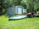 Gray storage shed, canoe, and lawn tractor in a grassy backyard at 24750 Ne 177Th Ter, Fort Mc Coy, FL 32134