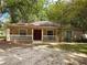 One-story house with red door, white railings, and mature trees at 6995 Se 22Nd Ave, Ocala, FL 34480