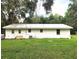 Back exterior of a single-story home with a metal roof, white siding, and green lawn at 10740 Ne 224Th Place Rd, Fort Mc Coy, FL 32134