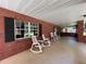 Brick front porch with rocking chairs and large windows at 9526 Sw 72Nd Ct, Ocala, FL 34476