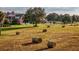 Open hay field with hay bales and a large home in the background at 17800 Se 237Th Ct, Umatilla, FL 32784