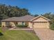 Single-story house with a tan exterior, brick driveway and landscaped yard at 13166 Se 86Th Cir, Summerfield, FL 34491
