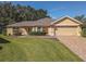 Front view of a single-story house featuring a tan stucco exterior, and a brick paved driveway at 13166 Se 86Th Cir, Summerfield, FL 34491