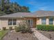 Tan house exterior with a welcoming front porch and landscaping at 13166 Se 86Th Cir, Summerfield, FL 34491