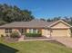 Single story home with a tan exterior, two-car garage, and well-manicured lawn at 13166 Se 86Th Cir, Summerfield, FL 34491