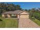 Single-story house with a tan exterior, brick driveway and landscaped yard at 13166 Se 86Th Cir, Summerfield, FL 34491