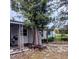 Rustic backyard with mature tree, stone patio, and storage shed at 34828 1St Ave, Leesburg, FL 34788