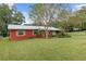 Red house with metal roof, landscaping, and yard at 2810 Se 8Th St, Ocala, FL 34471