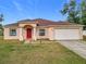 Single-story home with red door and attached garage, nicely landscaped lawn at 8335 Se 162Nd Pl, Summerfield, FL 34491
