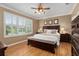 Main bedroom with king bed, wood floors, ceiling fan, and large windows at 11703 Se 91St Cir, Summerfield, FL 34491