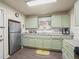 Efficient kitchen with light green cabinets and stainless steel refrigerator at 712 Sw 10Th Ave, Ocala, FL 34471
