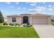 Tan house with mature landscaping and a two-car garage at 15596 Sw 13Th Cir, Ocala, FL 34473