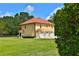 Exterior of a three-car garage yellow house with a red tile roof and lush green lawn at 1485 Se 59Th St, Ocala, FL 34480