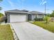 Gray house with white garage door, long driveway and landscaped yard at 227 Locust Pass Crse, Ocala, FL 34472