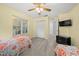 Well-lit bedroom featuring two beds, a ceiling fan, and access to a hallway at 17789 Se 113Th Ter, Summerfield, FL 34491