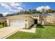 House exterior featuring a yellow facade, a three-car garage, and a well-manicured lawn at 15659 Sw 13Th Cir, Ocala, FL 34473