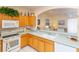 Bright kitchen with oak cabinets, white appliances, and a view into the adjoining living area at 15659 Sw 13Th Cir, Ocala, FL 34473