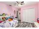 Bedroom with pink walls, wood-like floors, and a double door closet at 20390 Sw 57Th St, Dunnellon, FL 34431