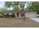 Tan one-story house with red door, attached garage, and landscaping at 20390 Sw 57Th St, Dunnellon, FL 34431