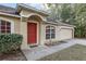 House exterior featuring a red front door and attached garage at 20390 Sw 57Th St, Dunnellon, FL 34431