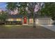 Tan one-story house with red door, attached garage, and landscaping at 20390 Sw 57Th St, Dunnellon, FL 34431