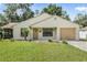 One-story house with beige siding, attached garage, and a well-maintained lawn at 21174 Sw Peach Blossom St, Dunnellon, FL 34431