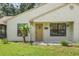 Front view of a house featuring a brown door, landscaping, and a beige exterior at 21174 Sw Peach Blossom St, Dunnellon, FL 34431