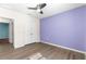 Bedroom with double doors to closet, purple accent wall, and grey wood-look floors at 3853 Se 99Th Ln, Belleview, FL 34420