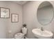 Simple bathroom with oval mirror, white sink, and toilet at 8469 Las Palmas Way, Wildwood, FL 34785