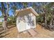 Small beige shed with white door, nestled amongst mature trees at 15330 Sw 59Th Ct, Ocala, FL 34473