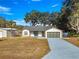 Single story home exterior view, featuring a two-car garage and a large driveway at 17757 Se 28Th Ln, Silver Springs, FL 34488