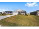 Landscaped yard with a one-story house, driveway, and other homes visible in the background at 6071 Sw 93Rd Loop, Ocala, FL 34476