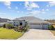 Single-story house with gray exterior, landscaping, and three-car garage at 3456 Conservation Trl, The Villages, FL 32163